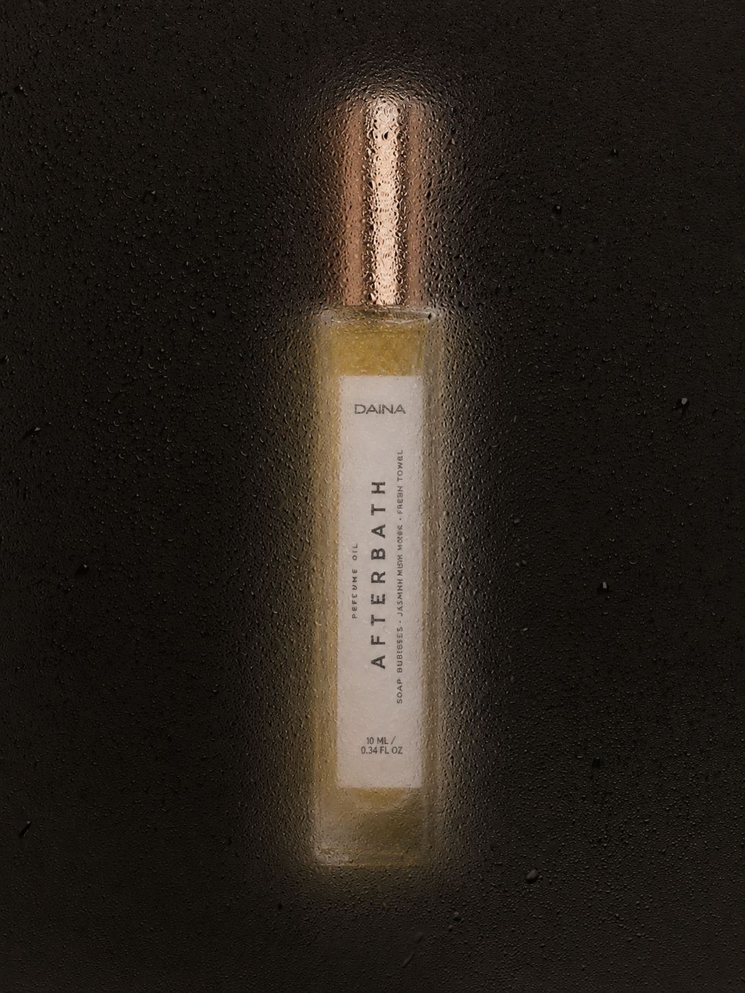 DAINA Afterbath perfume oil bottle lit against a dark, dewy background