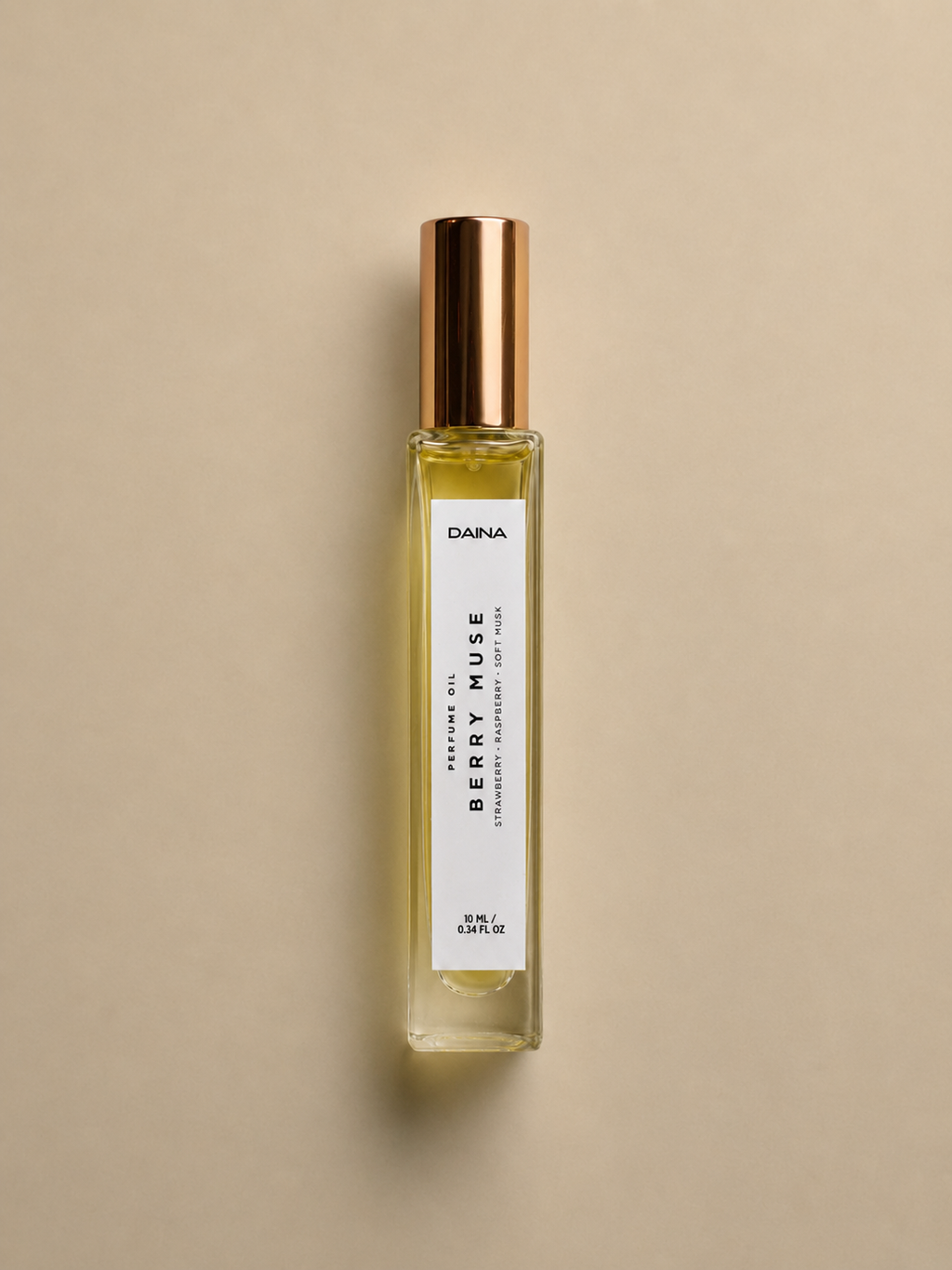 DAINA Berry Muse perfume oil bottle with gold cap on a beige background