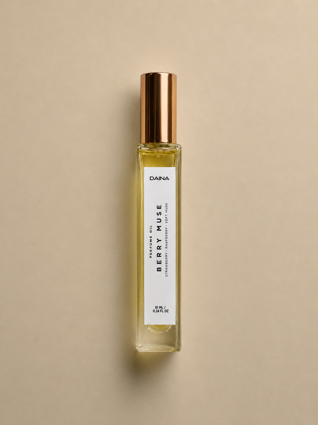 DAINA Berry Muse perfume oil bottle with gold cap on a beige background