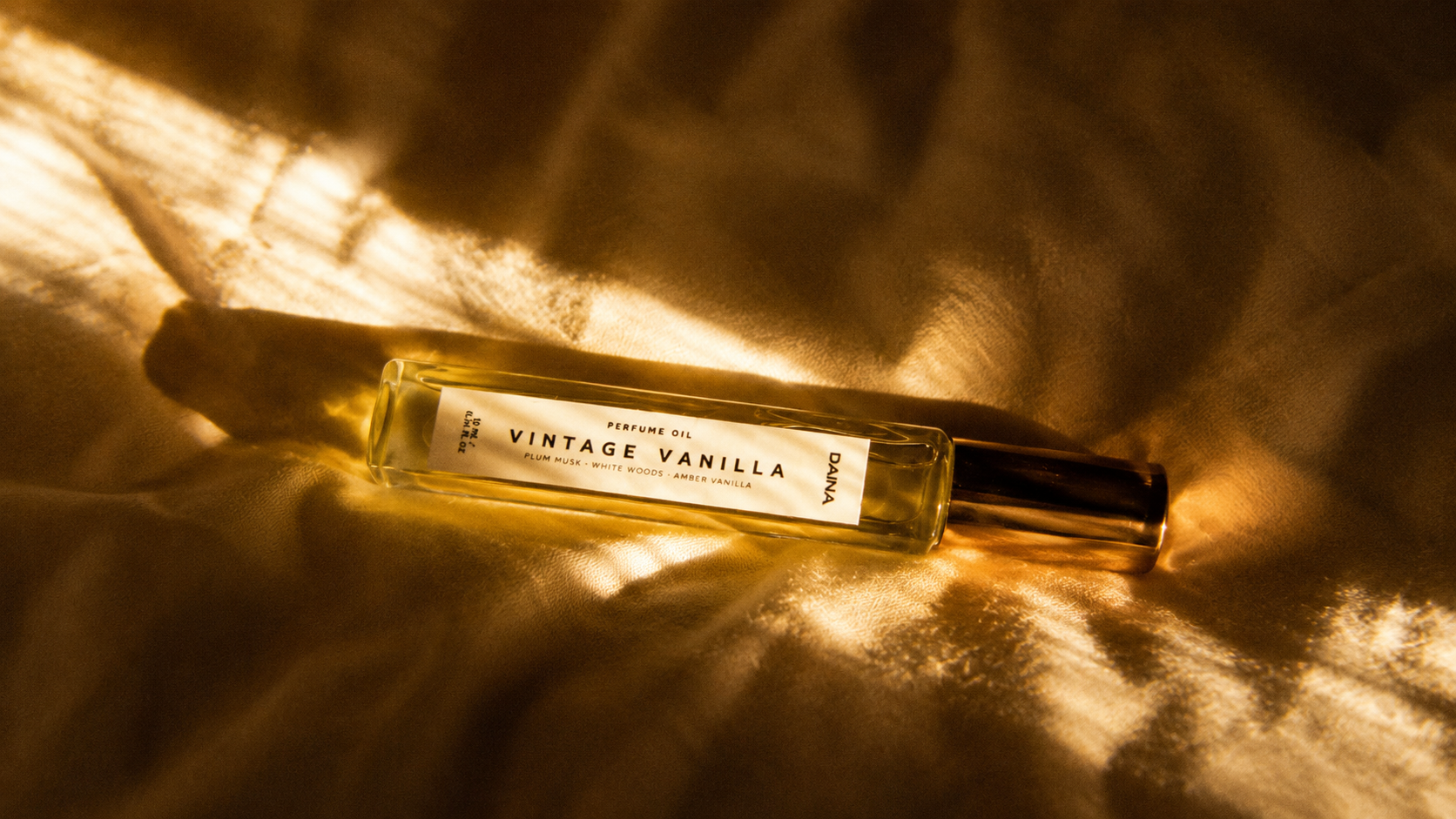 DAINA Vintage Vanilla perfume oil bottle in dramatic golden sunlight