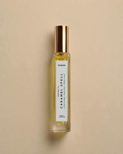 DAINA Caramel Spell perfume oil bottle with gold cap on a beige background