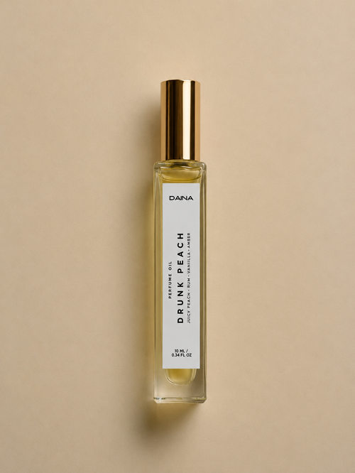 DAINA Drunk Peach perfume oil bottle, 10ml roll-on with gold cap, on beige background