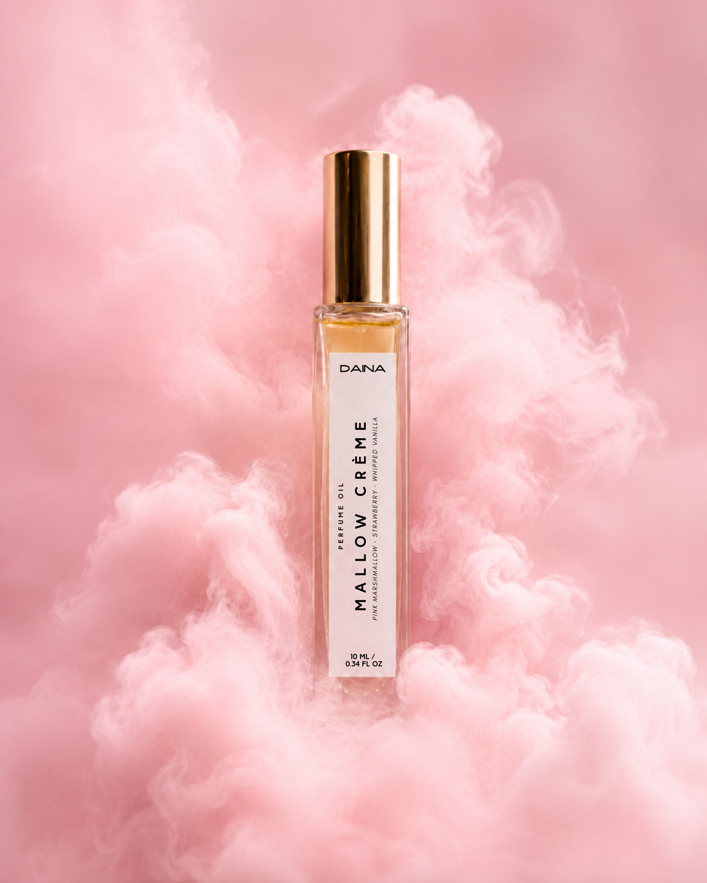 Mallow Crème perfume oil by Daina — clear glass roller bottle with gold cap, set against soft pink smoke