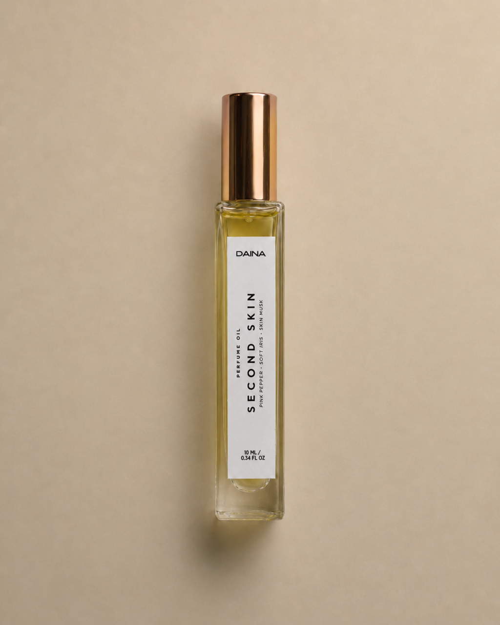 DAINA Second Skin perfume oil bottle with gold cap on a beige background