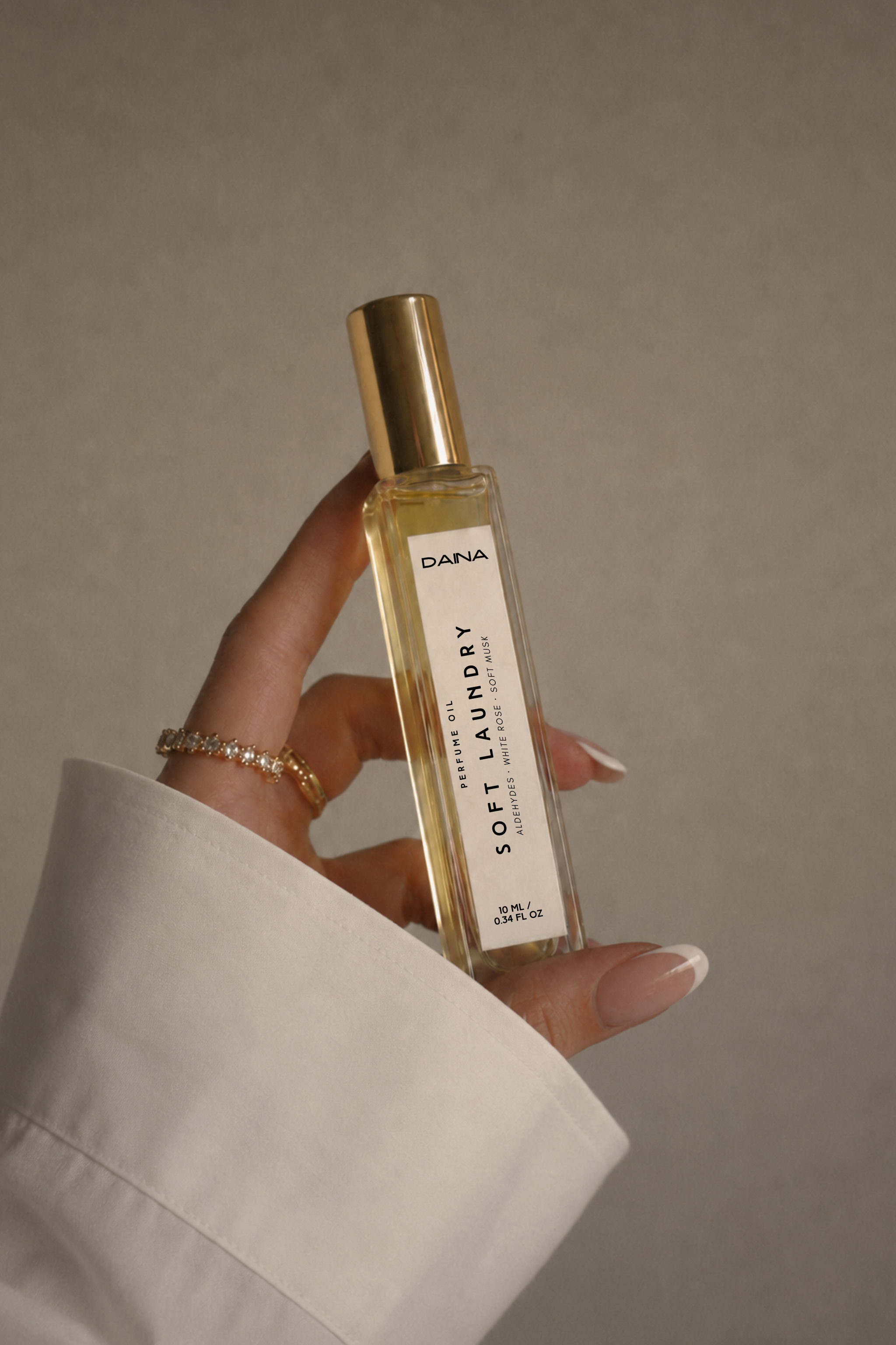 DAINA Soft Laundry perfume oil bottle held in a hand with a white shirt cuff