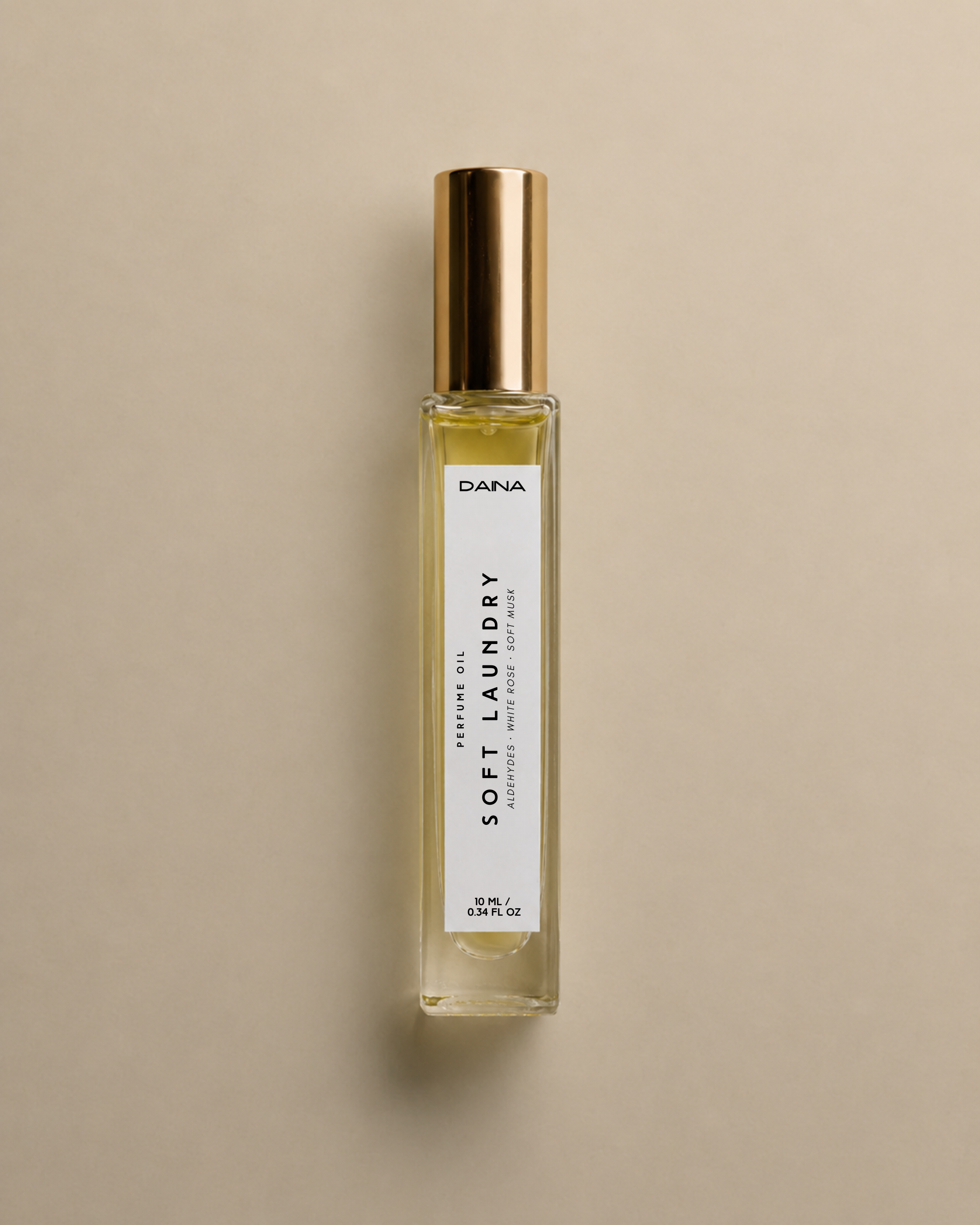 DAINA Soft Laundry perfume oil bottle with gold cap on a beige background